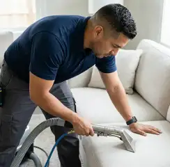 Professional upholstery cleaning technician using an extraction wand to deep-clean a fabric sofa, Glendale, AZ.