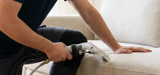 Professional upholstery cleaner deep-cleaning a fabric sofa with a handheld extraction tool, Glendale, AZ.